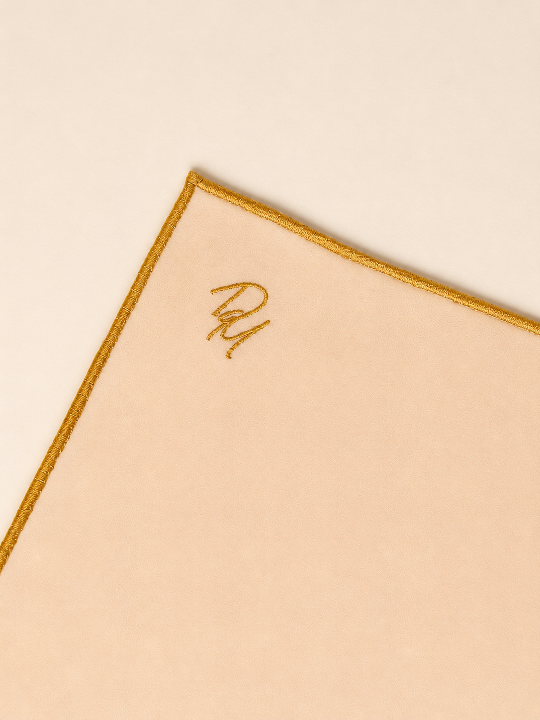 Aurora Scarf with gold trim and monogram on a beige background