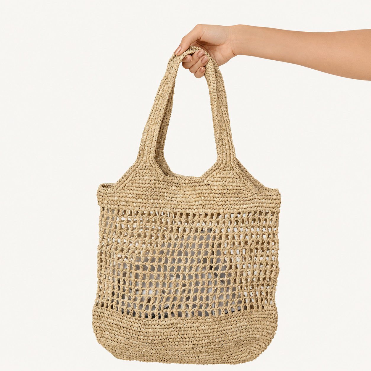 Hand holding a woven straw bag against a white background