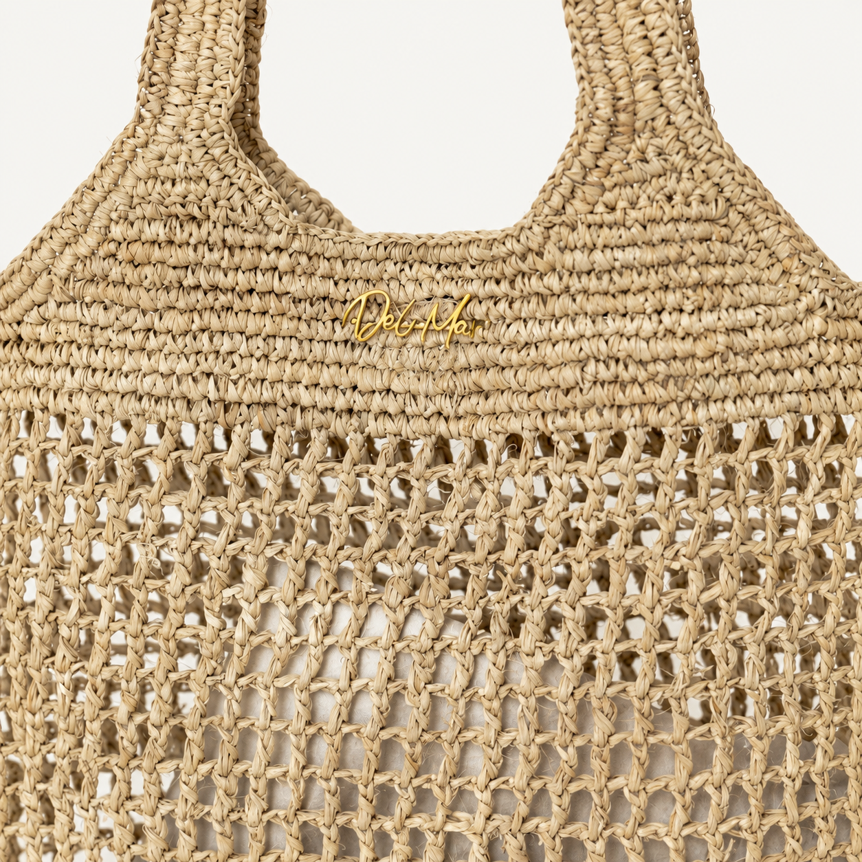 Close-up of a woven bag with 'Del Mar' branding on a light background