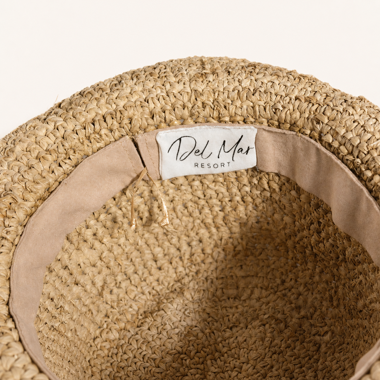 Close-up of a woven hat with a visible brand label on a white background